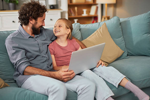 istock Father and daughter sharing a special moment with laptop on sofa 2247508400
