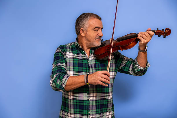istock Mature adult man playing violin on blue background 2247511538