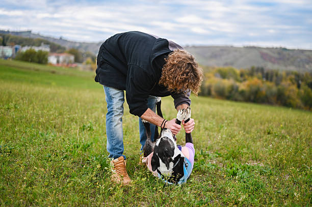 Young adult man playing with his dog outdoors on a grassy hill