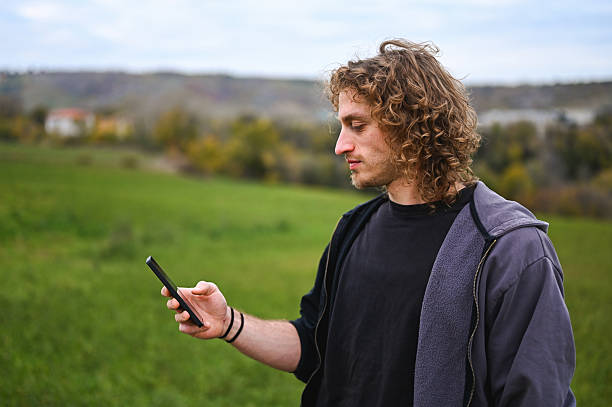 istock Young man looking at smartphone in rural field 2247514718
