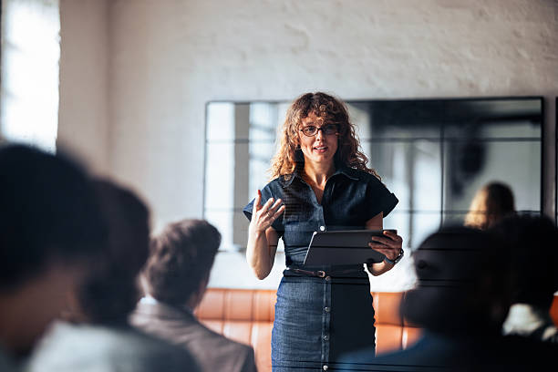 istock Confident Woman Presenter Leads Business Meeting With Tablet In Modern Office Setting 2247516958