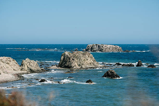 Coastal serenity: calm blue waters and rugged coastal rocks under a clear sky.