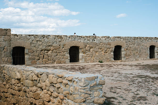 Old stone fortress wall with blue sky and white clouds.