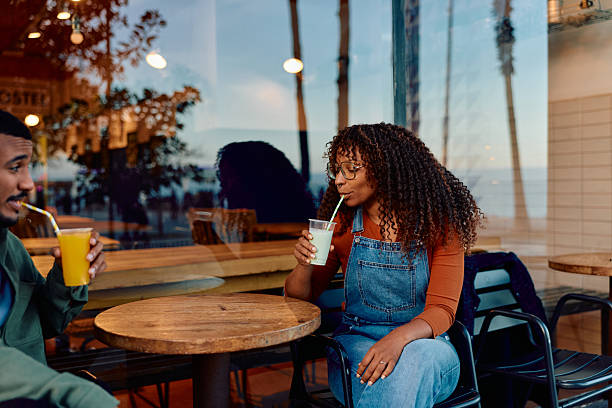 istock Couple enjoying cold drinks at cafe window 2247523089