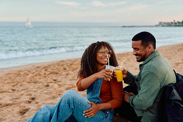 istock Happy couple toasting drinks enjoying sunset on beach 2247525014