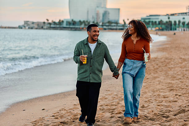 istock Happy couple holding hands walking on Barcelona beach 2247526540