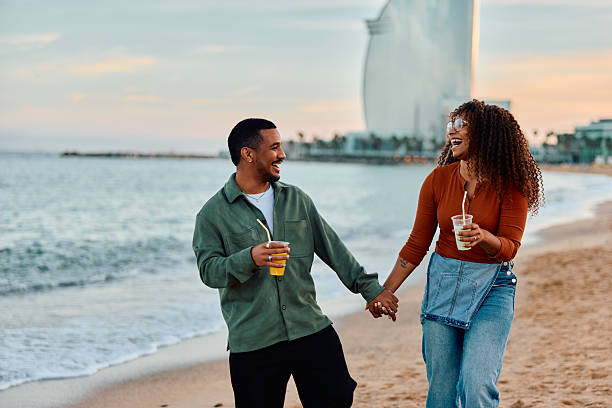 istock Couple walking on beach holding hands laughing in Barcelona 2247526545