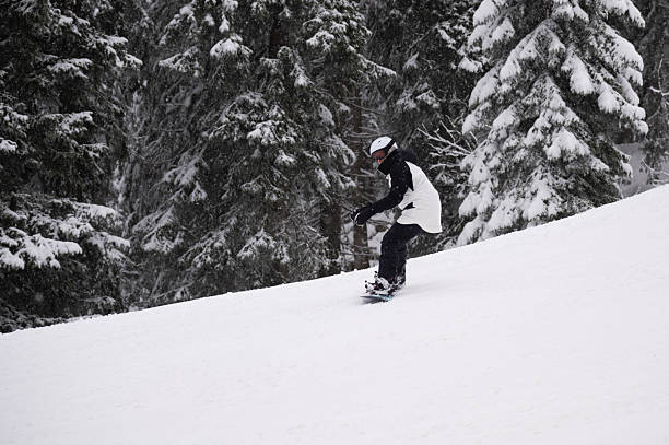 A snowboarder dressed in red is captured as they make a sharp turn on a snowy mountain terrain. The action creates a flurry of snow, showcasing the energy and thrill of winter sports in the cold, misty atmosphere.