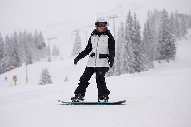 istock Woman snowboarding down a snowy mountain slope 2247531414
