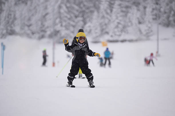 Young child wearing a helmet and goggles learning to ski on a snowy slope, enjoying winter sport activities