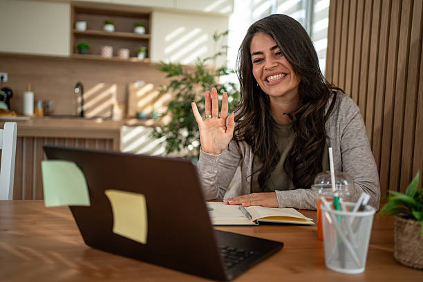 istock Woman waving while having video call from home 2247532342
