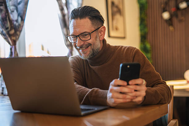 istock Mature man working remote using laptop and phone 2247533897