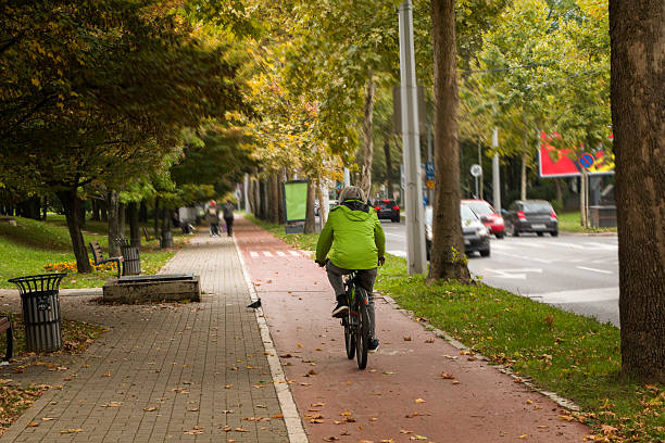 Man  in the green jacket rides a bicycle in the city . Concept of healthy lifestyle and sustainable mobility. Man rides a bicycle in the city on a bicycle path