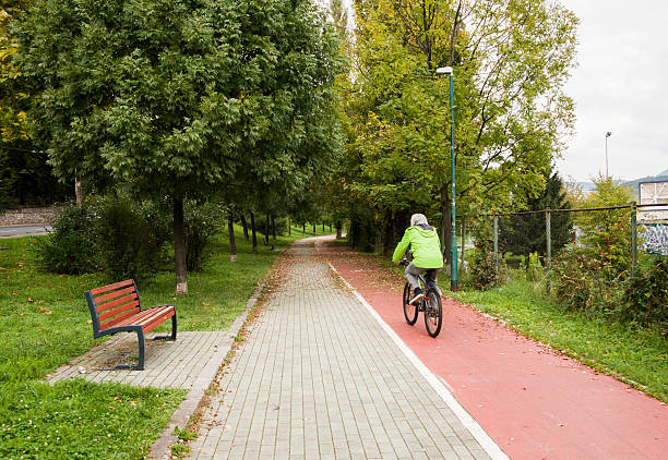 Man  in the green jacket rides a bicycle in the city . Concept of healthy lifestyle and sustainable mobility. Man rides a bicycle in the city on a bicycle path