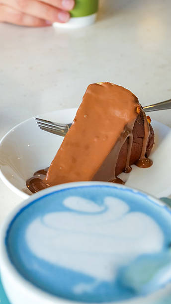 istock Delicious chocolate cake slice on a white plate with a fork, accompanied by a vibrant blue latte art coffee drink, showcasing dessert indulgence 2247535832