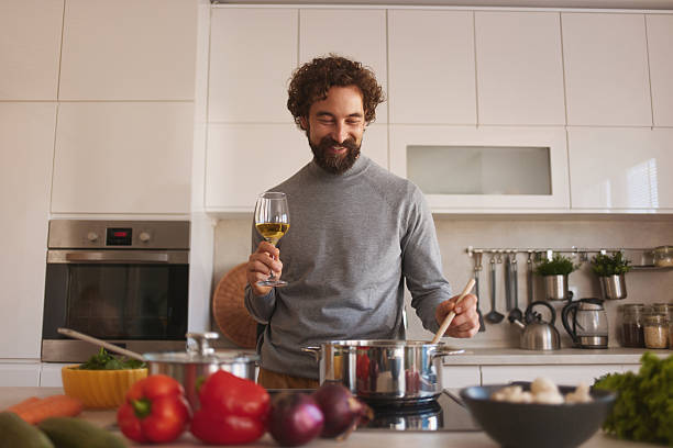 istock Man cooking healthy meal, enjoying white wine 2247537058