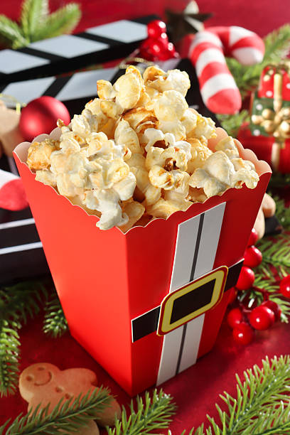 Vertical photo of popcorn falling above glass bowl on orange background, dynamic motion scene perfect for food, cinema, or lifestyle concepts