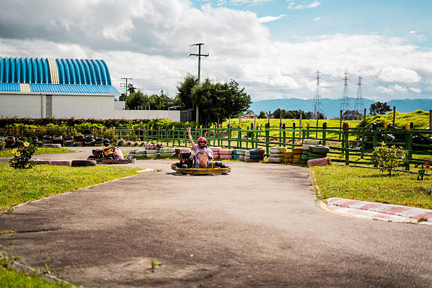 A single go-kart driver navigates a winding outdoor track in a green landscape. The scene captures the excitement of recreational karting in a playful environment.