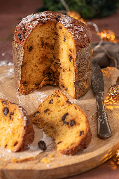 istock A delicious Panettone with raisins, partially sliced to reveal its moist interior, dusted with powdered sugar and presented on a wooden board with a silver knife 2247542012