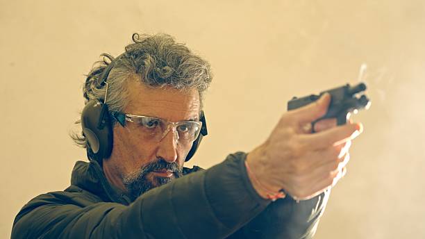 istock Man Firing Handgun. Shooting A Weapon For Defence Training 2247542620
