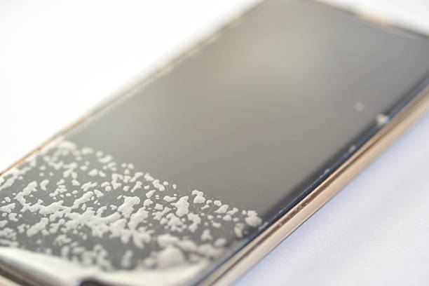 Close-up of smartphone with water damage on screen displaying moisture accumulation.