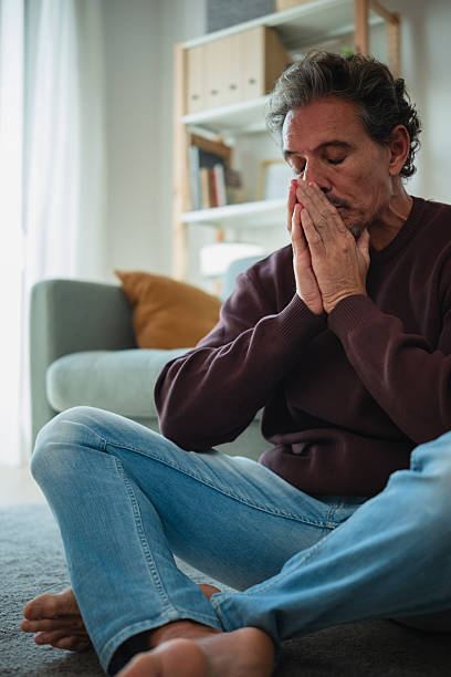 istock Man praying sitting home experiencing mental health issue 2247543527