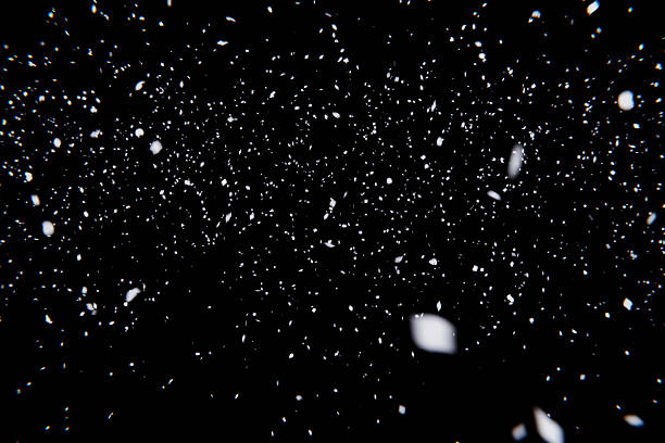 istock Falling Snow Effect Overlay. Abstract texture of white particles and blurred bokeh on a dark, pure black backdrop. Perfect for winter, holiday, or atmospheric photo compositing. 2247545024
