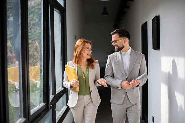 istock Business colleagues walking and talking in modern office hallway 2247546236