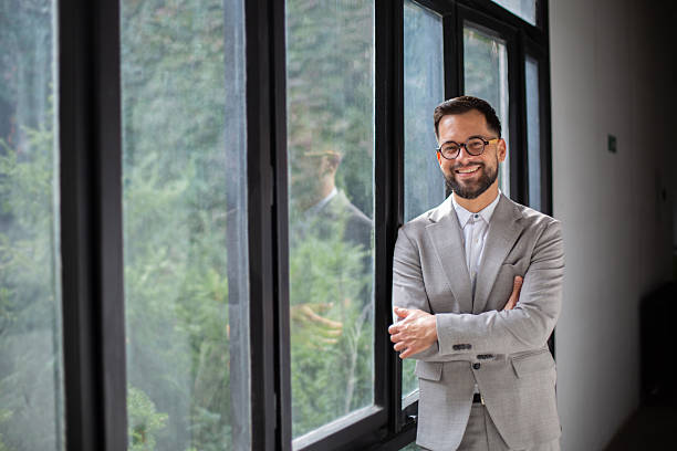 istock Smiling confident businessman standing by window in office 2247546269