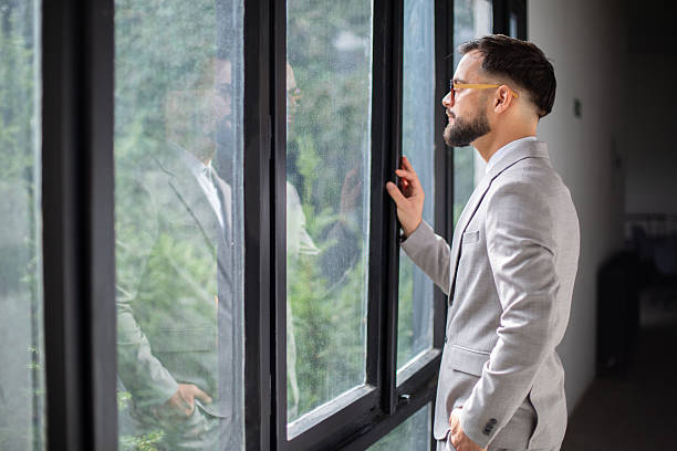 istock Businessman looking through window contemplating future success 2247546308