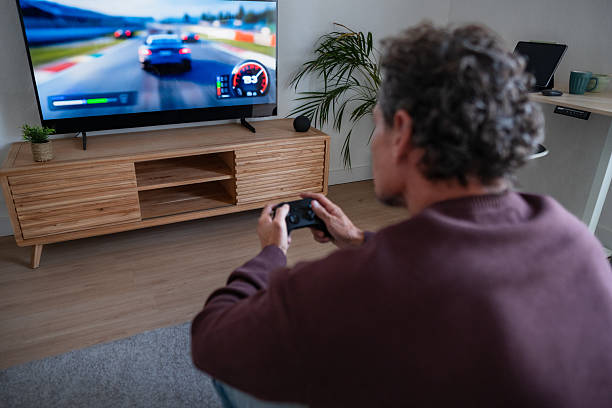 istock Man playing car racing video game on television 2247547387