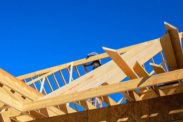 istock Construction worker on new building roof under timber studs working with wooden beams 2247560888