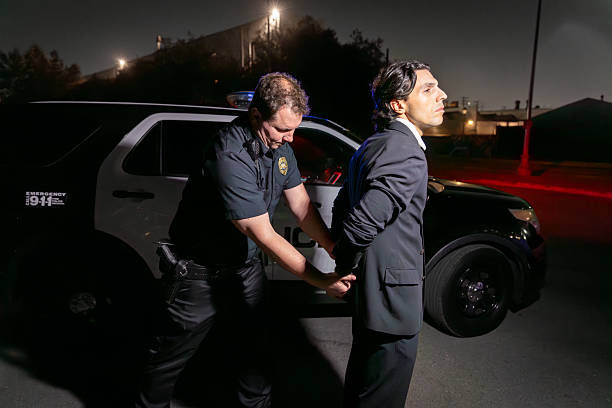 istock Police Officer Handcuffing Man in Suit at Night 2247565820