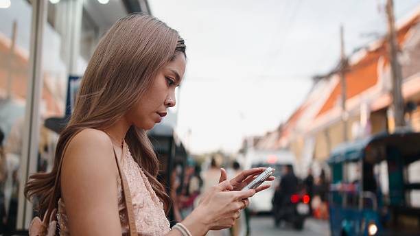 istock Young woman using mobile phone outdoors, connecting with technology in bangkok 2247566961
