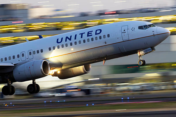 Portland, Oregon, USA - October 17, 2025: A United Airlines 737 departs Portland International at dusk with the illuminated airport terminal in the background.