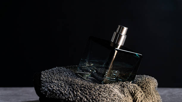 istock Glass perfume bottle tilted on soft fabric with angled lighting, showcasing reflections and premium design, fitting for fragrance promotions and elegant lifestyle visuals. 2247578965