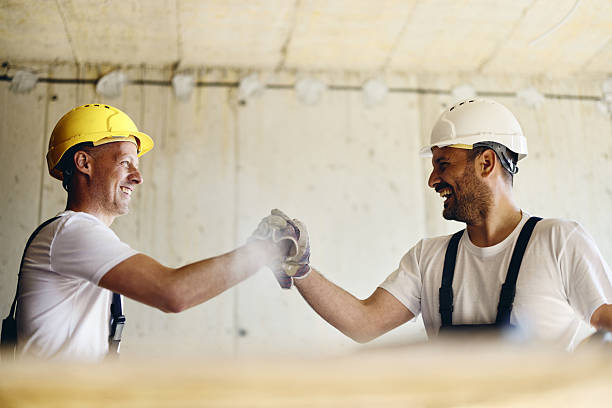istock Cheerful manual workers greeting each other at construction site. 2247581242