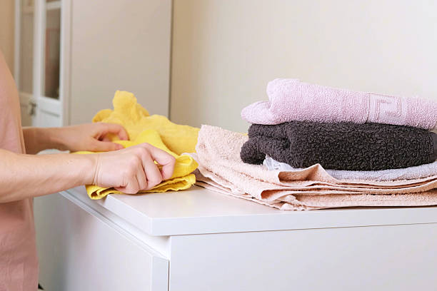 istock Female hands folding bright yellow towel on top of clean colorful stack 2247583762