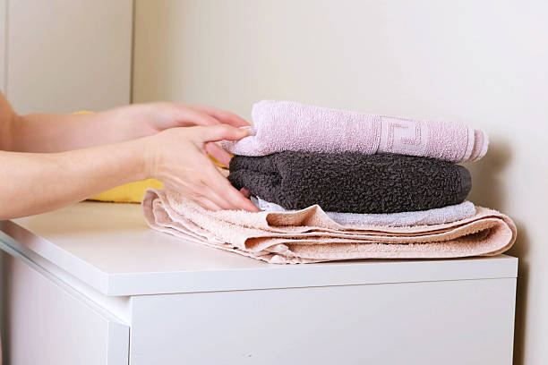 istock Female hands folding and stacking clean soft towels on white cabinet 2247583765