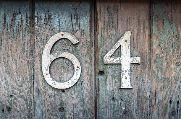 istock Weathered house number 64 on an old wooden surface 2247586086