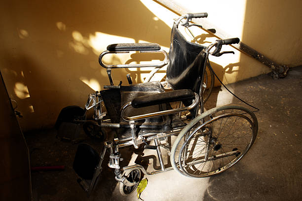 old wheelchair rusting and dirty left in a corner with sunlight and shadow