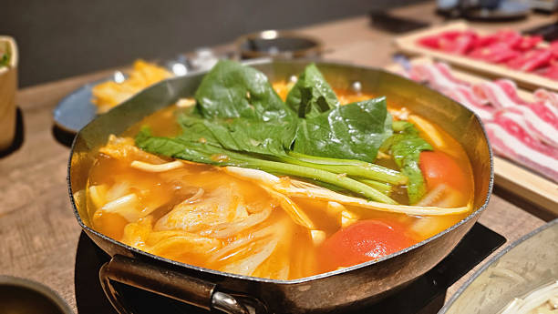 Japanese hotpot bowl filled with vibrant tomato broth, fresh vegetables, sliced meats, tofu, and warm steam, cozy shabu-shabu with rich red soup, nutritious ingredients, and a flavorful dining moment