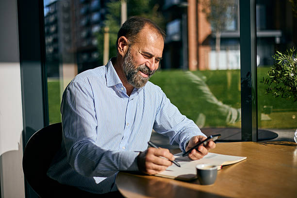 istock Business Professional Working At Windowed Table With Phone, Paper, And Coffee Ambience 2247588452