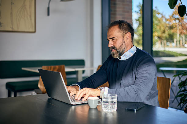istock Professional Man Working on Laptop in Modern Cafe Setting During Daytime 2247588456
