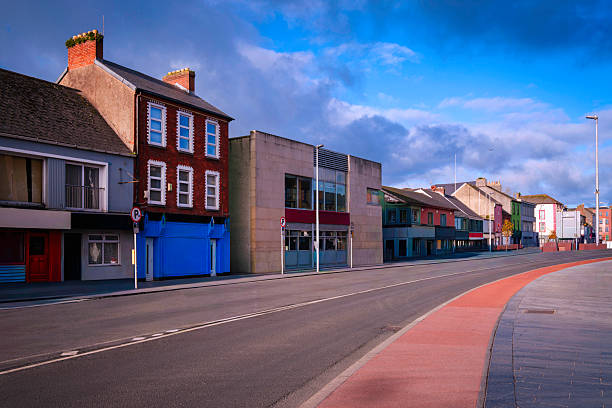Adare historic district downtown landscape in early morning with charming buildings, stores, and a clean curved local road getting ready for a busy day with tourists in County Limerick, Ireland