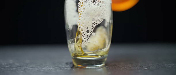 istock Golden beer with foamy head in glass on dark surface 2247591920