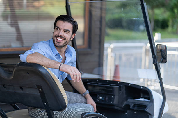 istock Smiling man driving golf cart on vacation at a resort 2247592034