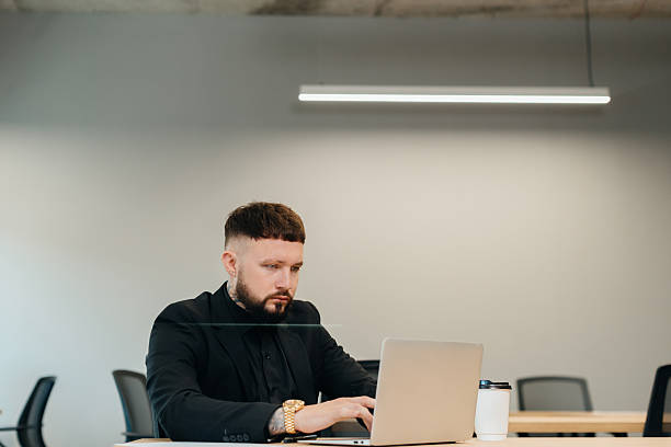 istock Tattooed businessman working on laptop in modern office 2247592545