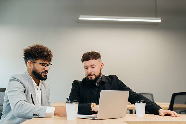 istock Businessmen collaborating on project using laptop in office 2247593880