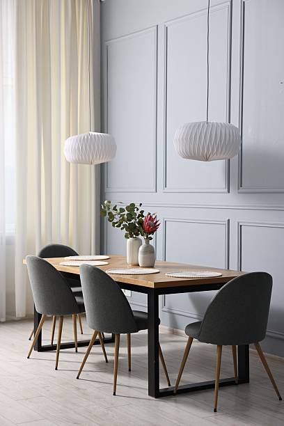 istock Soft chairs, table and vases with plants in stylish dining room 2247595843